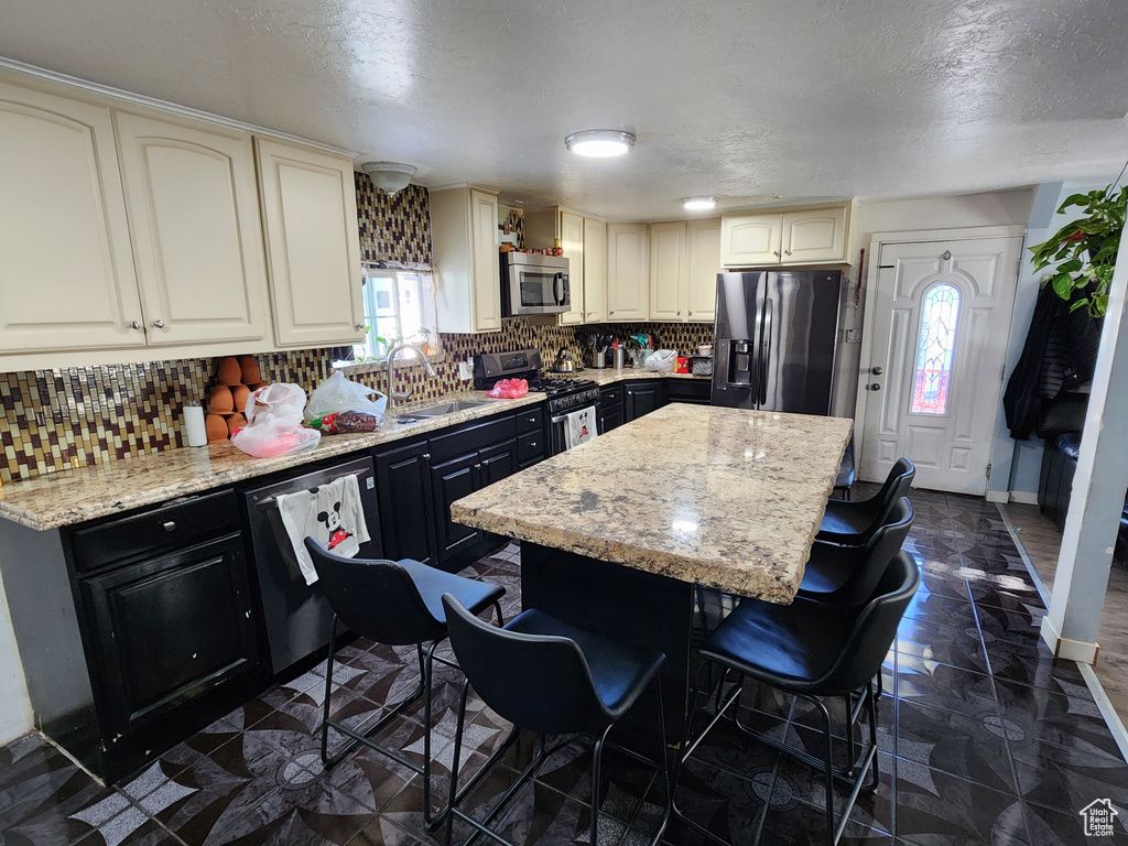 Kitchen featuring a kitchen island, backsplash, stainless steel appliances, and dark tile floors