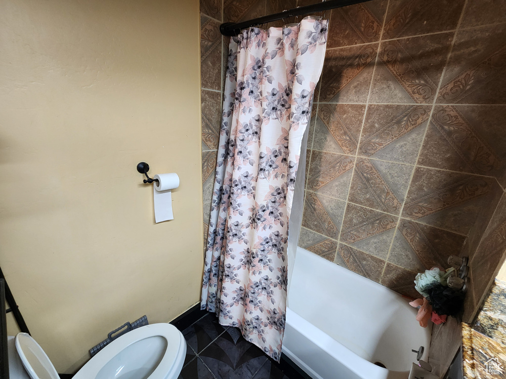 Bathroom featuring tile flooring, toilet, and shower / tub combo with curtain