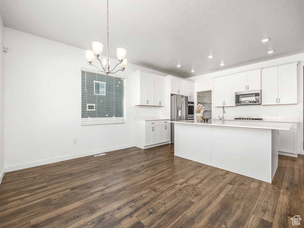 Kitchen featuring white cabinets, dark hardwood / wood-style floors, stainless steel appliances, and a chandelier