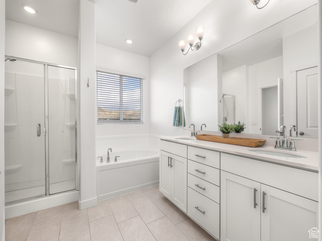 Bathroom featuring tile floors, double sink, vanity with extensive cabinet space, and separate shower and tub