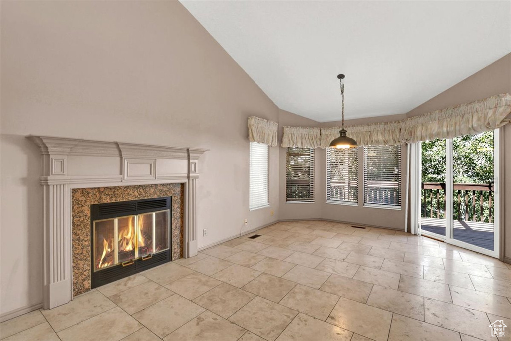 Unfurnished dining area with a wealth of natural light, light tile floors, a high end fireplace, and high vaulted ceiling