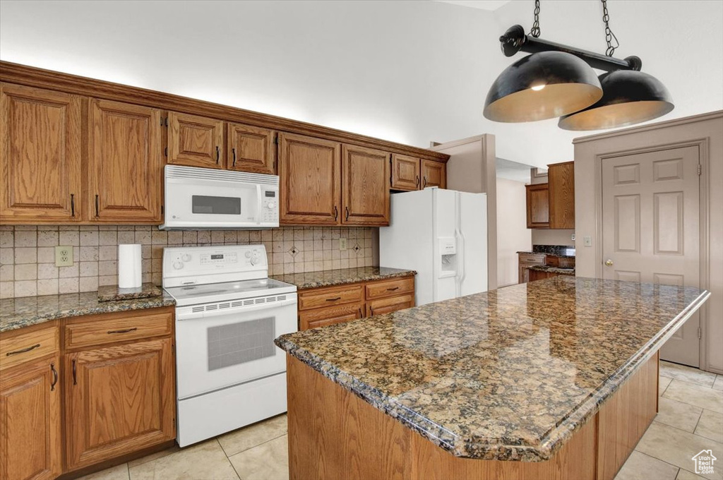 Kitchen featuring tasteful backsplash, white appliances, a center island, and light tile floors