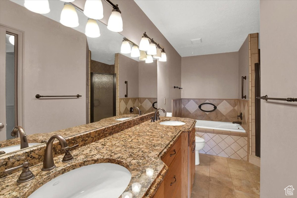 Full bathroom featuring shower with separate bathtub, tile floors, double sink vanity, and toilet