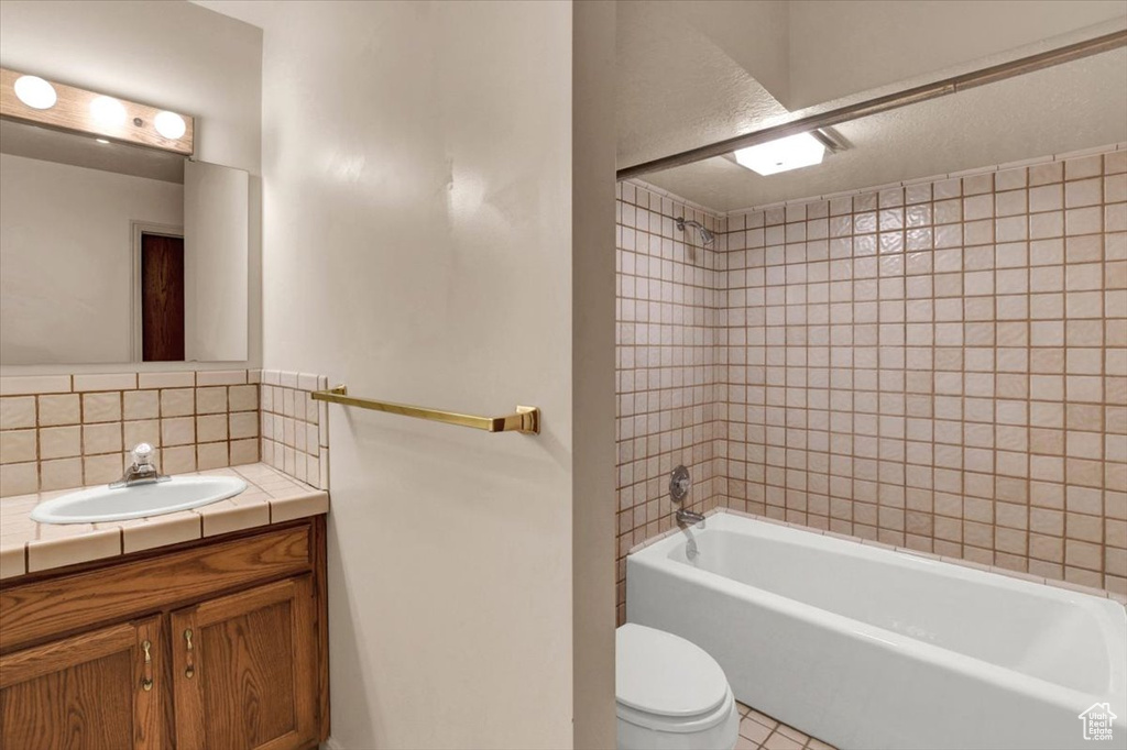 Full bathroom with vanity, toilet, tile flooring, and tiled shower / bath combo