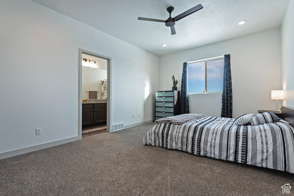 Carpeted bedroom featuring ensuite bath and ceiling fan