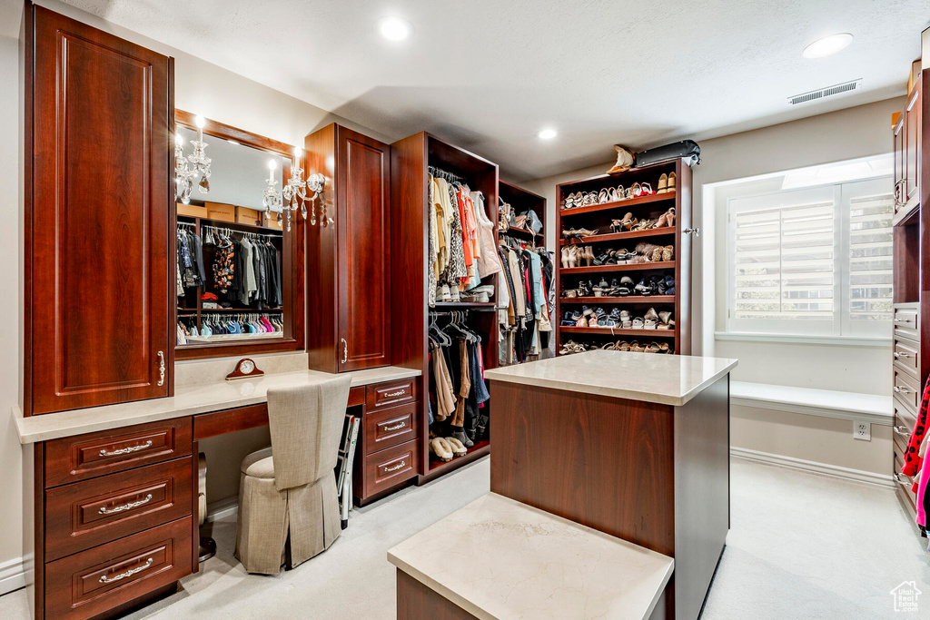 Spacious closet with light carpet and built in desk