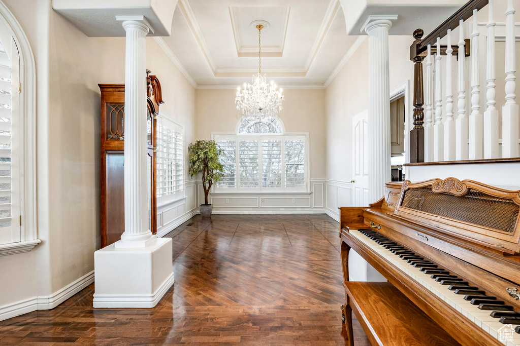 Entrance foyer with a chandelier, dark hardwood / wood-style flooring, and ornate columns