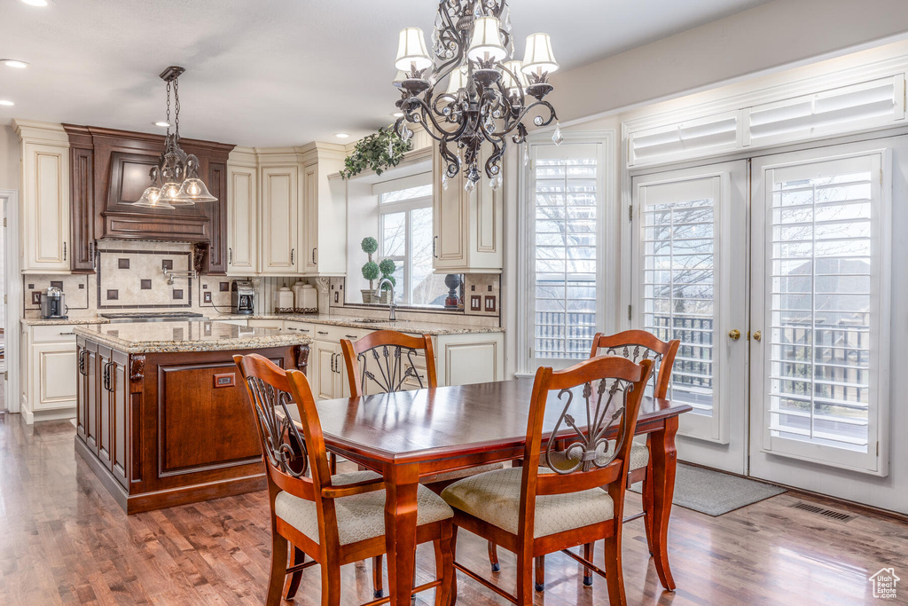 Dining room with hardwood / wood-style floors, a wealth of natural light, and a chandelier