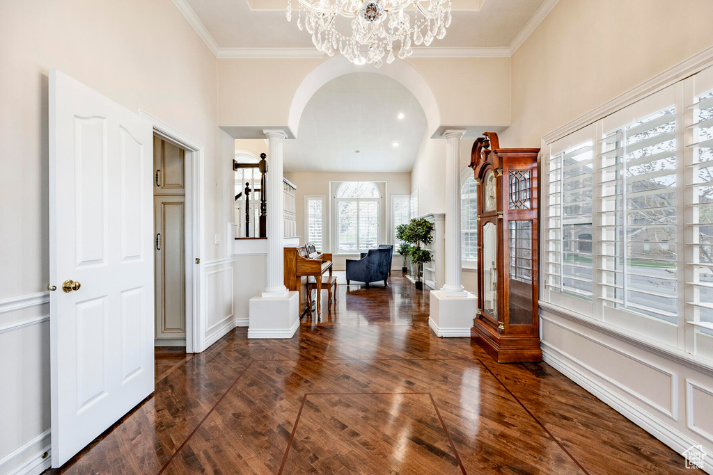 Foyer featuring a chandelier, ornamental molding, ornate columns, and dark hardwood / wood-style floors