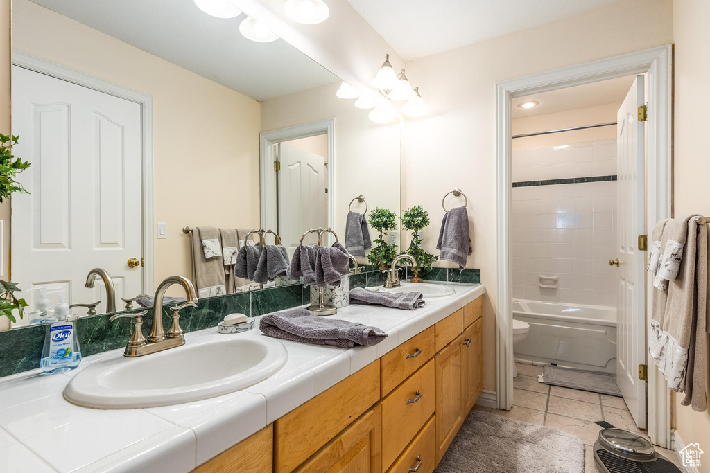Full bathroom featuring shower / bath combo, toilet, tile floors, and dual vanity