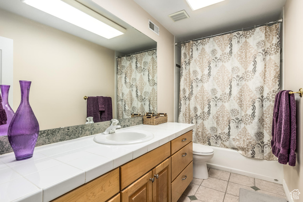 Full bathroom with toilet, tile floors, shower / tub combo with curtain, and large vanity