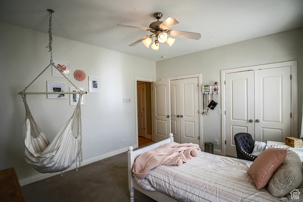 Bedroom featuring dark carpet, ceiling fan, and two closets