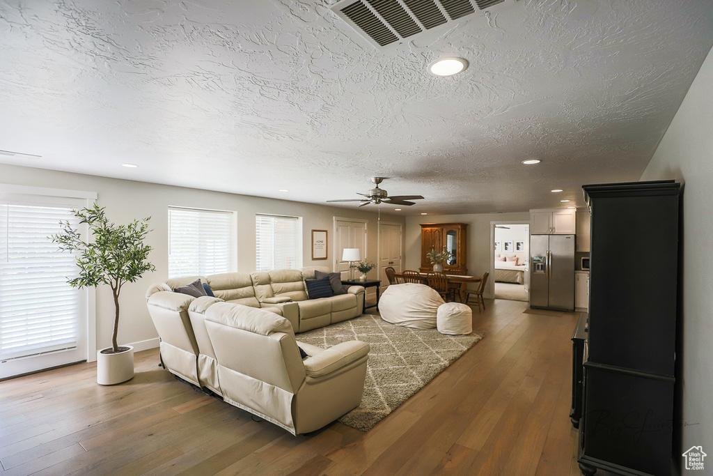 Living room featuring a textured ceiling, hardwood / wood-style floors, and ceiling fan
