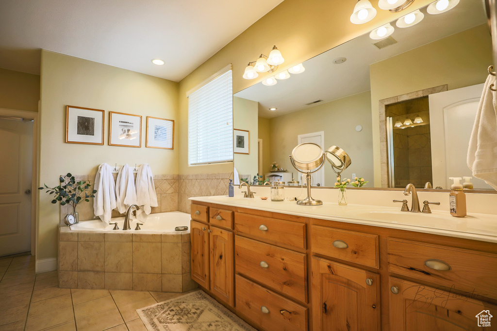 Bathroom with oversized vanity, tiled bath, tile floors, and dual sinks