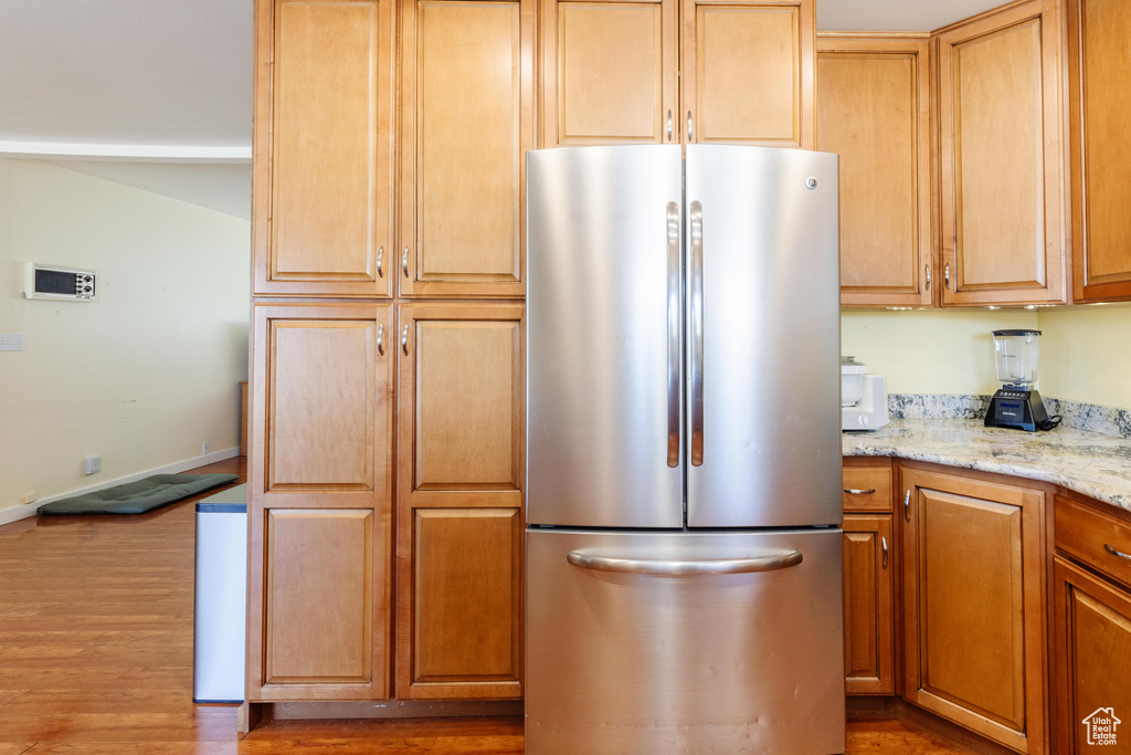 Kitchen featuring stainless steel fridge, light stone countertops, and dark hardwood / wood-style floors