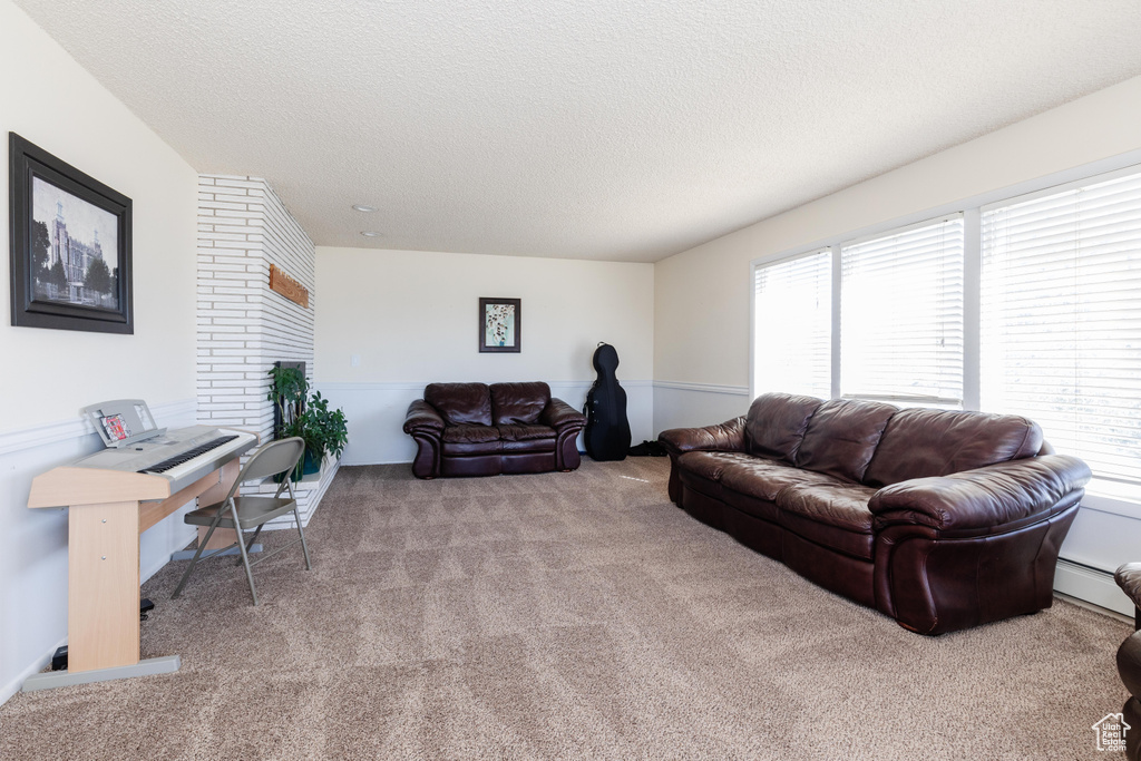 Living room with light colored carpet, baseboard heating, and a textured ceiling