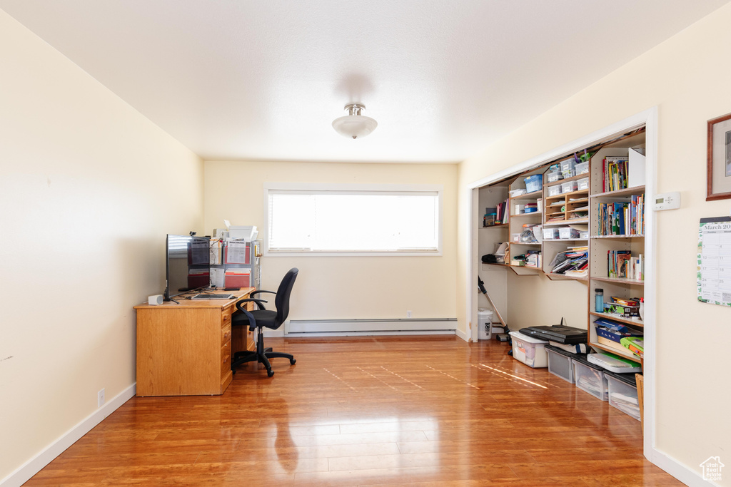 Office area with a baseboard radiator and light hardwood / wood-style floors