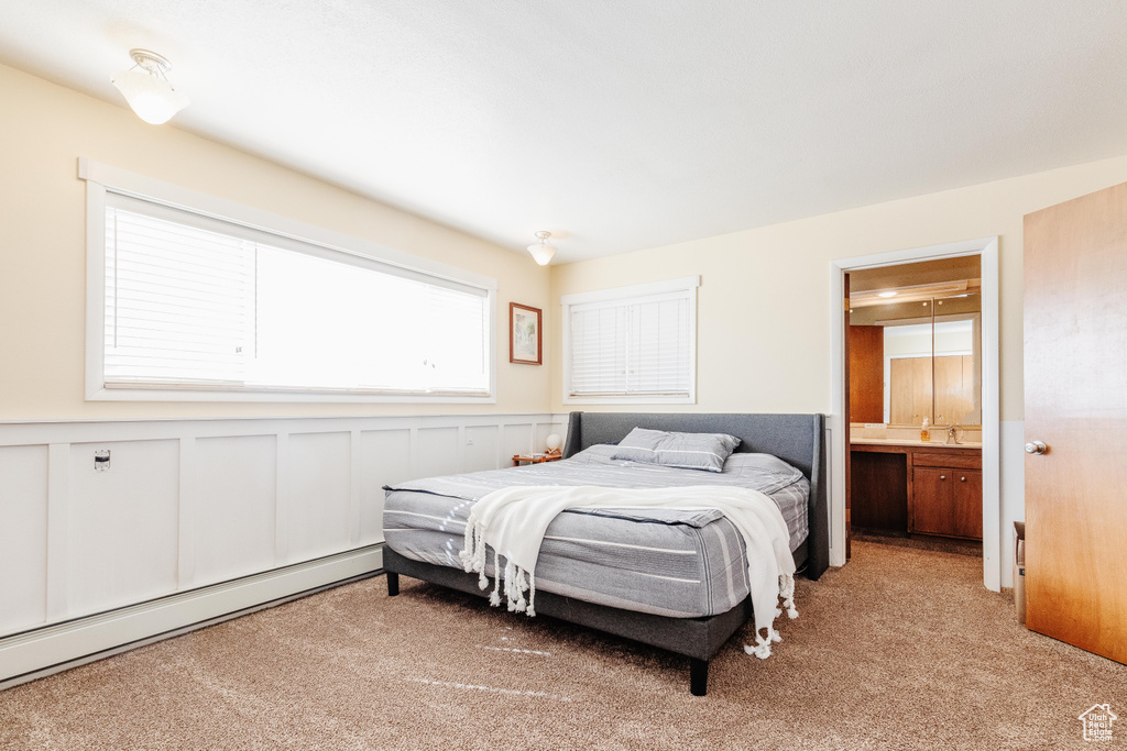 Carpeted bedroom featuring baseboard heating and connected bathroom