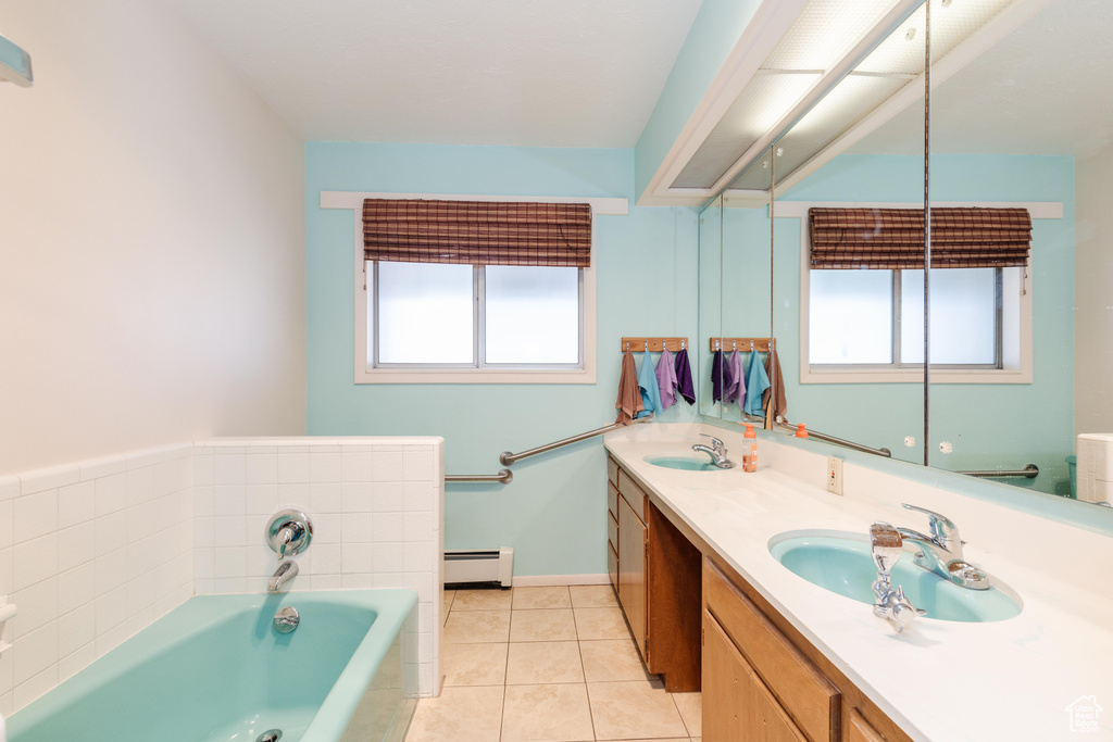 Bathroom with plenty of natural light, dual bowl vanity, a bathing tub, and a baseboard heating unit