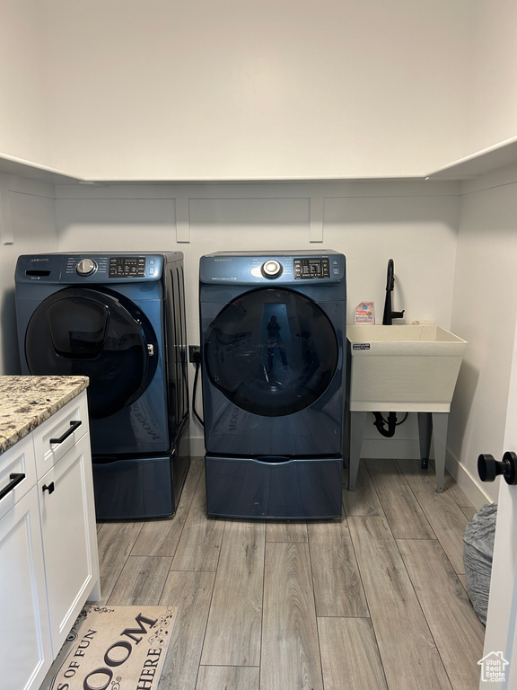 Laundry room with cabinets, light hardwood / wood-style floors, and washer and dryer