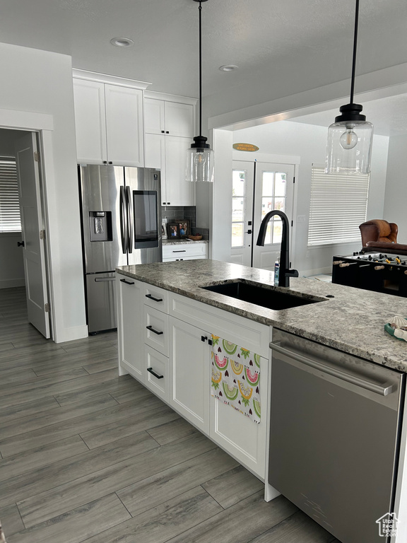 Kitchen featuring sink, decorative light fixtures, light stone counters, white cabinets, and stainless steel appliances