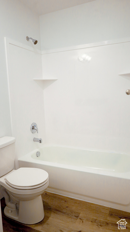 Bathroom featuring toilet, shower / bathing tub combination, and hardwood / wood-style floors