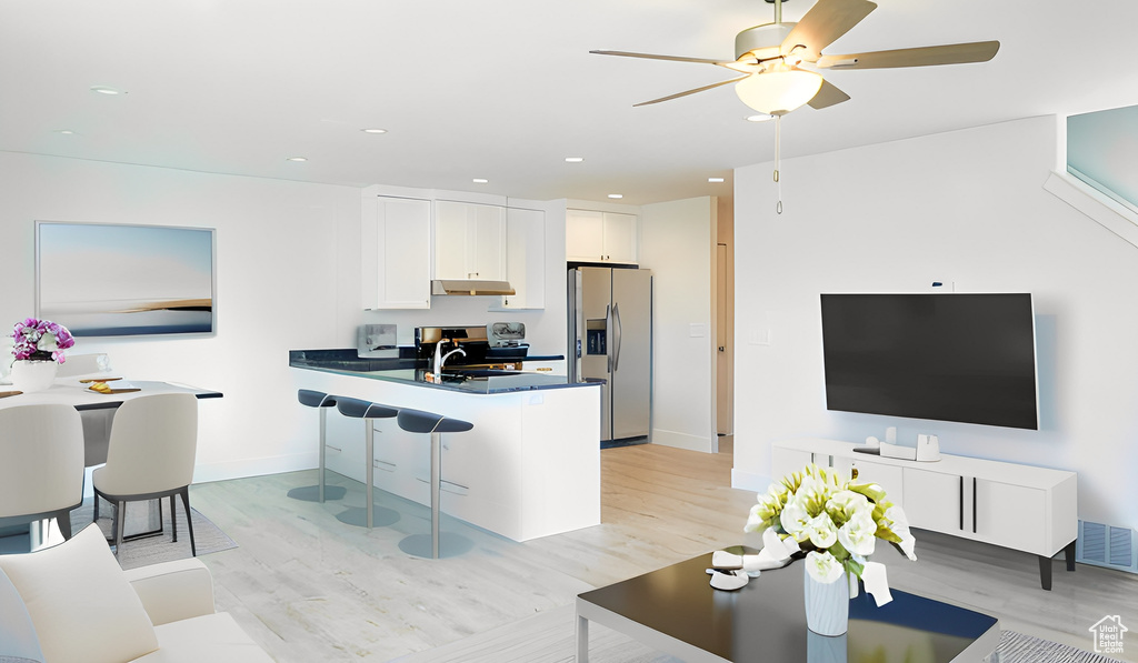 Kitchen featuring white cabinets, ceiling fan, light hardwood / wood-style floors, a kitchen breakfast bar, and stainless steel fridge with ice dispenser
