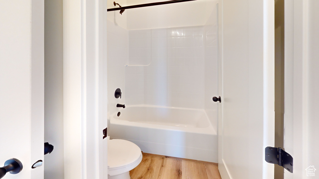 Bathroom featuring hardwood / wood-style flooring, washtub / shower combination, and toilet