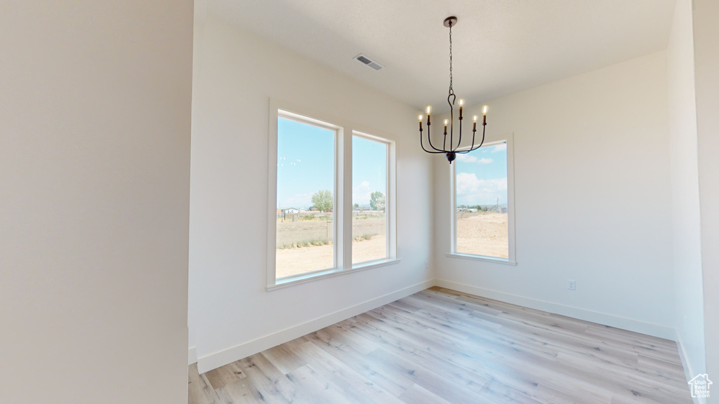 Unfurnished room featuring a chandelier and light hardwood / wood-style floors