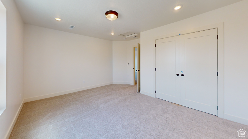 Unfurnished bedroom with light colored carpet and a closet