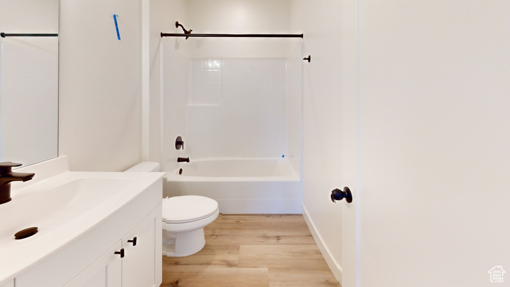 Full bathroom featuring wood-type flooring, vanity, washtub / shower combination, and toilet