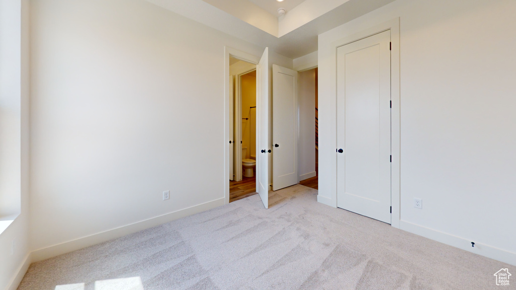 Unfurnished bedroom featuring connected bathroom and light colored carpet