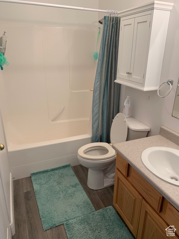 Full bathroom with shower / bathtub combination with curtain, vanity, toilet, and wood-type flooring