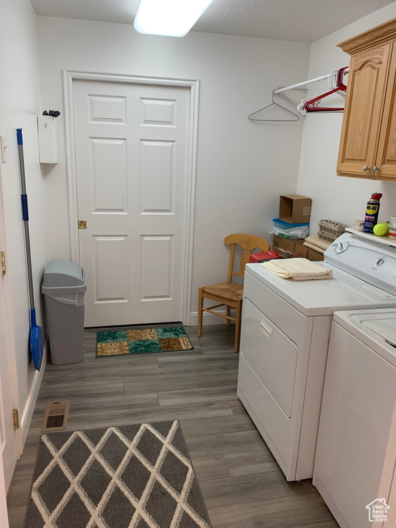 Clothes washing area featuring dark hardwood / wood-style flooring, cabinets, and washer and clothes dryer