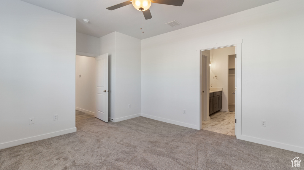 Unfurnished bedroom with ensuite bathroom, light colored carpet, and ceiling fan