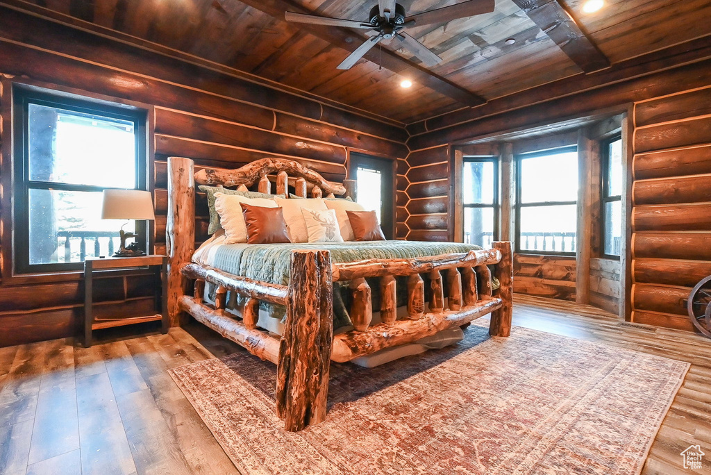 Bedroom featuring dark hardwood / wood-style flooring, wood ceiling, rustic walls, and ceiling fan