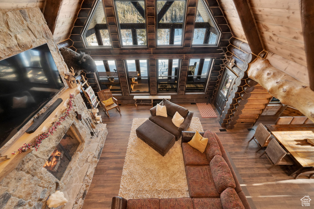 Unfurnished living room featuring dark hardwood / wood-style flooring, log walls, beamed ceiling, and high vaulted ceiling