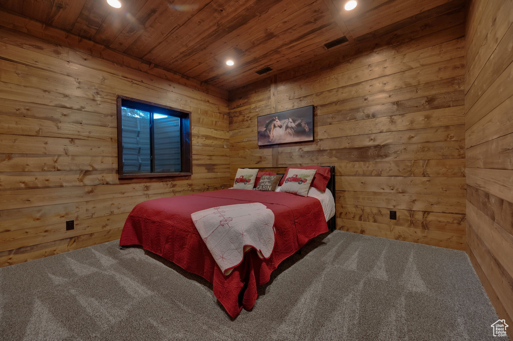 Bedroom with wood walls, wooden ceiling, and carpet floors