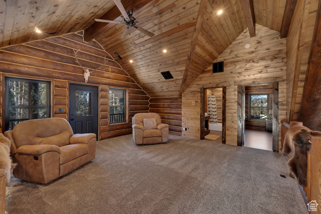 Carpeted living room featuring ceiling fan, high vaulted ceiling, wooden ceiling, beam ceiling, and rustic walls