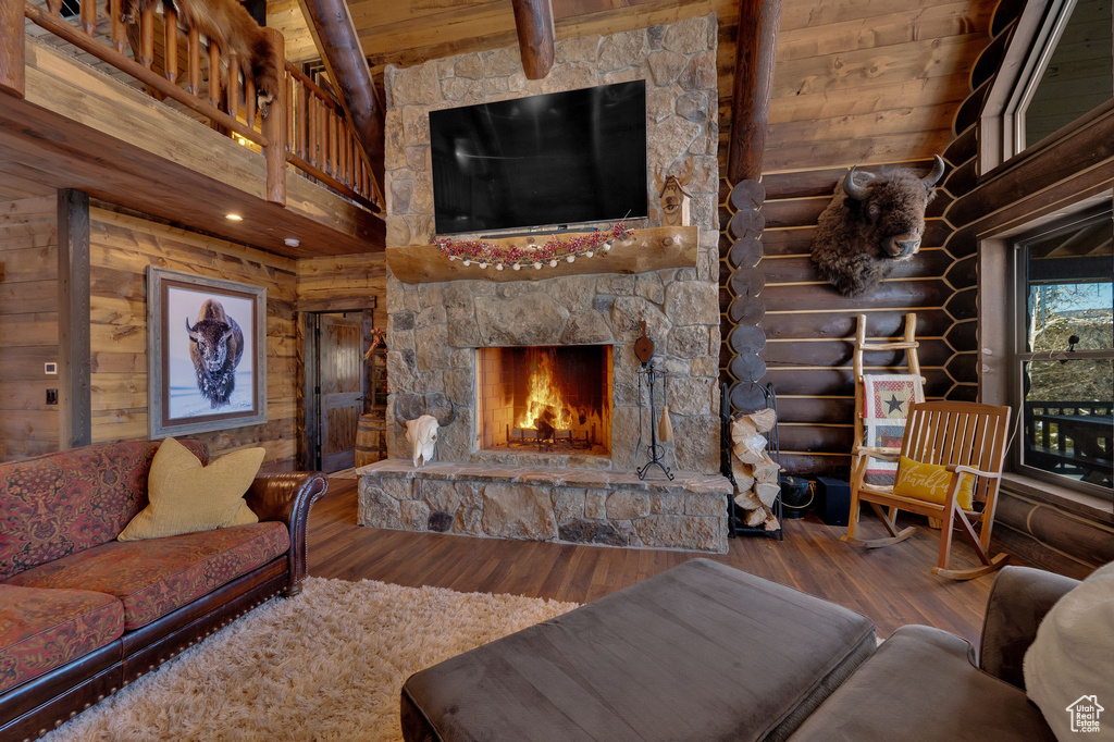 Living room with dark wood-type flooring, a fireplace, rustic walls, and high vaulted ceiling