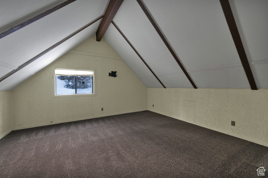 Additional living space with vaulted ceiling and dark carpet