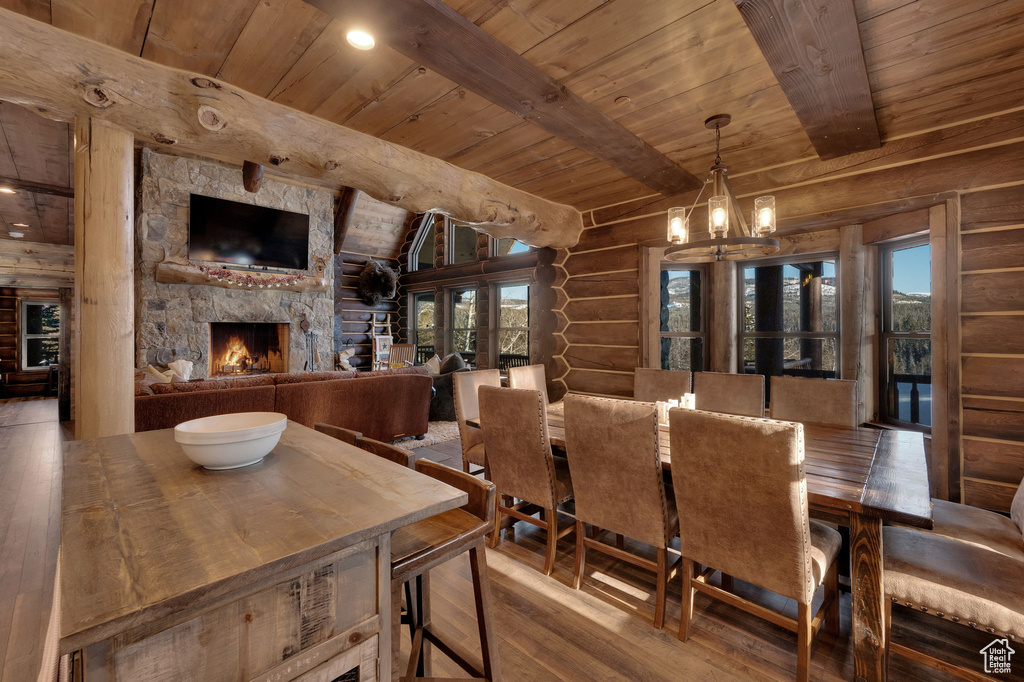 Dining area with a stone fireplace, dark hardwood / wood-style floors, vaulted ceiling with beams, and rustic walls