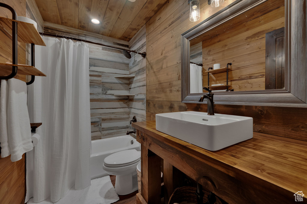 Full bathroom featuring shower / tub combo with curtain, wooden walls, wooden ceiling, toilet, and vanity