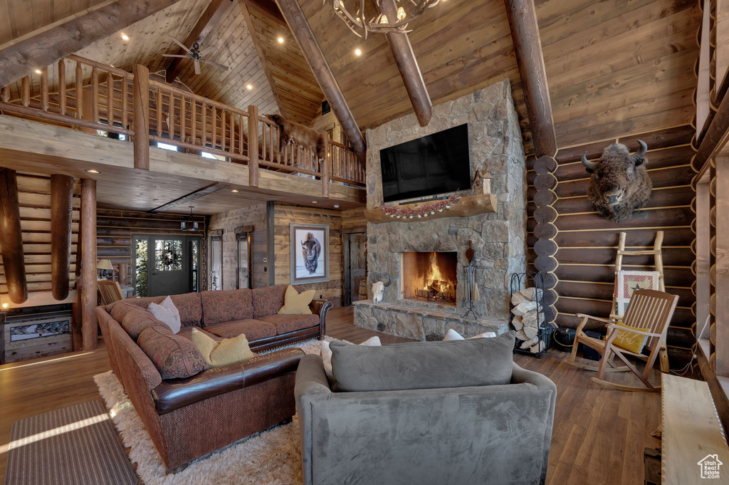 Living room featuring dark hardwood / wood-style flooring, high vaulted ceiling, log walls, and wood ceiling