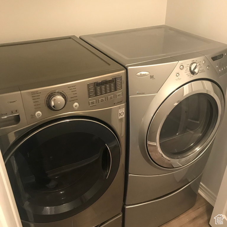 Laundry room with washing machine and dryer and hardwood / wood-style flooring