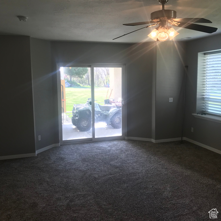 Spare room featuring dark carpet and ceiling fan