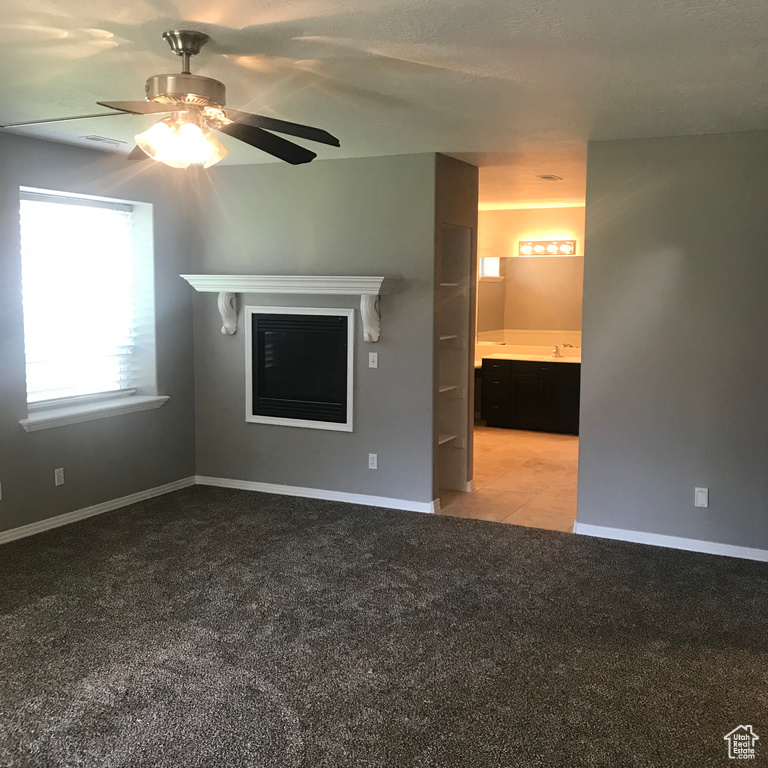 Unfurnished bedroom with light carpet, connected bathroom, sink, and ceiling fan