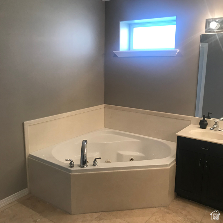 Bathroom featuring tile flooring, a washtub, and vanity