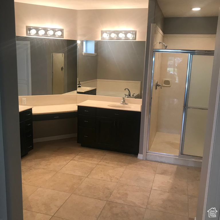 Bathroom featuring a shower with shower door, tile flooring, and vanity