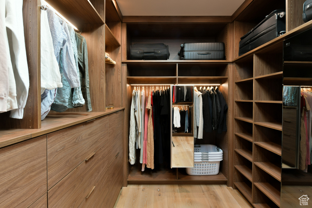 Walk in closet with light hardwood / wood-style floors